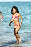 Young Christina Milian in striped bikini on a beach