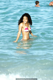 Young Christina Milian in striped bikini on a beach